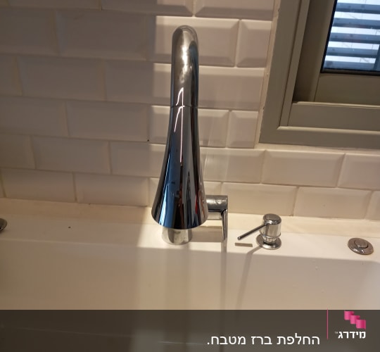 ברז נירוסטה מעל כיור לבן עם ניקוז